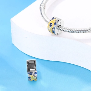 Detail of silver bead charm with yellow enamel and blue crystals on stone blocks