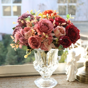Floral arrangement with vintage silk peonies and roses in a tall glass vase by the window