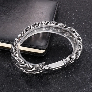 Close-up of men's vintage steel Cuban link bracelet with engraved Greek key patterns