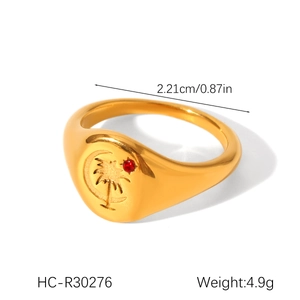 Detail of gold signet ring featuring coconut tree and moon relief with red gemstone