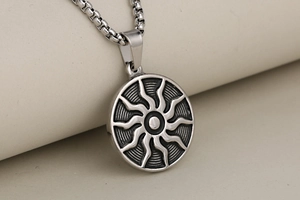 Macro detail of silver sunburst pendant with oxidized relief and box chain necklace