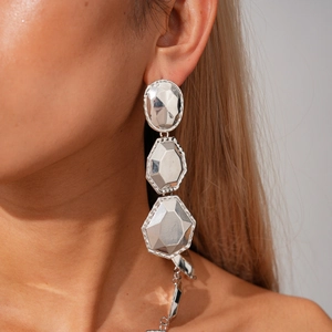 Detailed view of silver geometric layered drop earrings on model with metallic finish