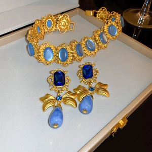 Detail of vintage gold bow earrings with blue teardrop stones in a jewelry box