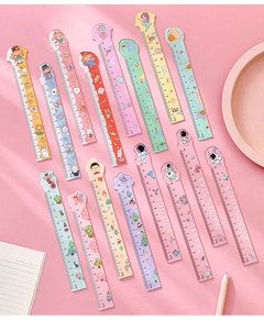 Flat lay of colorful 15cm cartoon plastic rulers with cute designs on pink desk