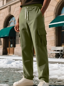 Detail of olive green corduroy joggers with cargo pockets and drawstring waist on model
