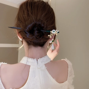 Detail of wooden hair stick with flower tassels worn in a classic updo hairstyle