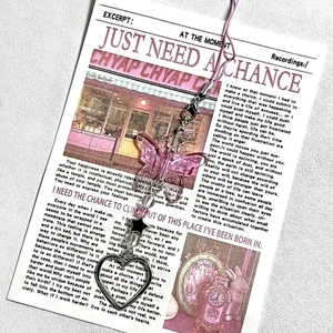 Pink acrylic butterfly charm with black star and silver heart on aesthetic newspaper background