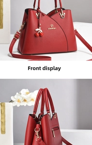 Detail view of red lychee pattern handbag with gold hardware and cherry pendant