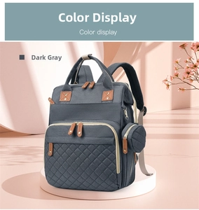 Close-up of gray quilted diaper bag with brown leather pulls and matching mini pouch