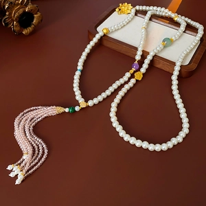 Detailed macro view of long beaded necklace featuring white pearls and pink crystal tassels