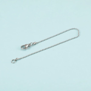 Minimalist silver ball chain bracelet with lobster clasp on a light blue background