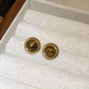 Detail of vintage golden round earrings with brown tiger eye stone on a velvet tray