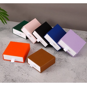 Various colored drawer jewelry boxes with white ribbon handles arranged in a fan shape