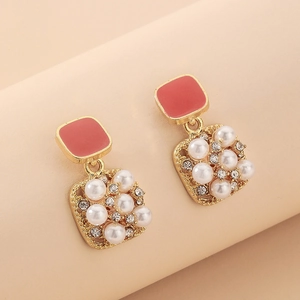 Detailed close-up of pink enamel square earrings with pearls and gold accents
