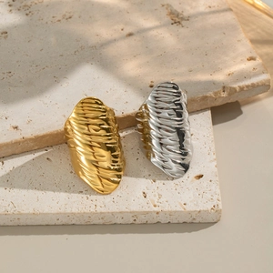 Unique hip-hop style rippled texture rings in gold and silver on beige travertine stone