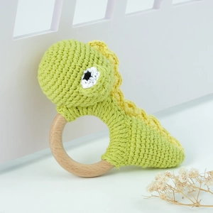 Detail of a handmade crochet dinosaur rattle toy on a natural wooden ring for infants