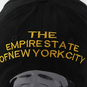 Detailed close-up of gold 3D embroidery on black cotton twill baseball cap fabric