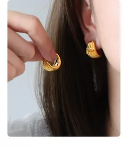 Detail of 18K gold plated U-shaped earrings featuring vertical textured wave patterns