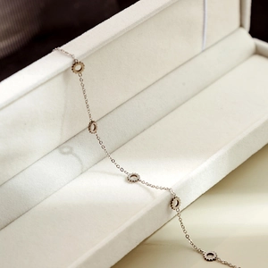 Detailed shot of a minimalist silver chain with gear-shaped pendants in a white jewelry box