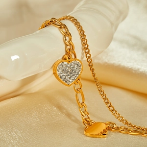 Dettaglio del bracciale doppio strato dorato con cuore in zirconi e ciondolo a specchio