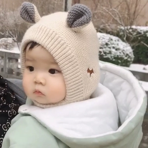 Detailed close-up of a knitted baby winter hat with cute ears in a snowy outdoor setting