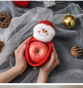 Close-up of red knitted Christmas gift bag with plush snowman held in hands