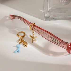 Detail of gold starfish, shell, and blue coral charms hanging on pink glass frames
