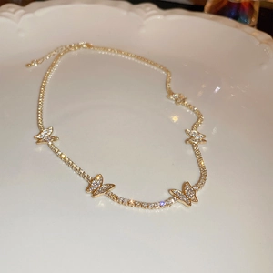 Detailed view of gold butterfly necklace with shimmering micro-pave diamonds on white plate