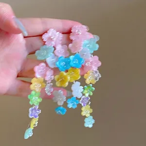 Détail de boucles d'oreilles fleurs colorées avec pampilles longues et pétales en résine