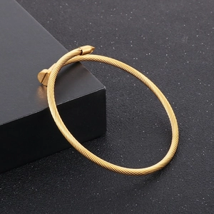 Detailed close-up of golden nail cuff bracelet with twisted rope texture on black stand