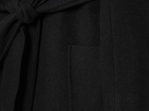 Detail of black wool blend coat showing waist tie knot and precision edge stitching