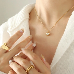 Detail of 18k gold plated heart pendant necklace and matching ring on female model