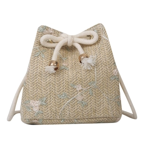 Floral embroidered straw bucket bag with drawstring closure and crossbody strap