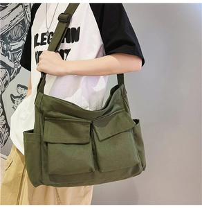 Detail of army green canvas crossbody bag with multi-pocket design and wide shoulder strap
