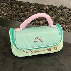 Close-up of mint green makeup bag with pink handle and cute cartoon crab illustration