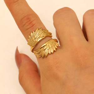 Detailed close-up of golden hollowed-out wing ring with fine feather texture