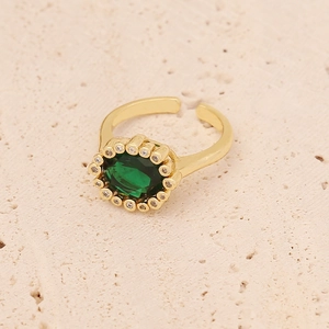 Detail of gold open ring featuring a green zircon center stone with halo accents