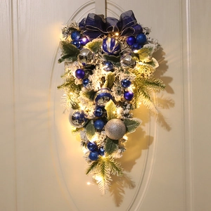 Blue and silver Christmas teardrop swag with velvet bow and LED lights on a white door