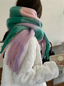 Detail view of colorful rainbow checkered scarf with long fringe tassels in green and pink