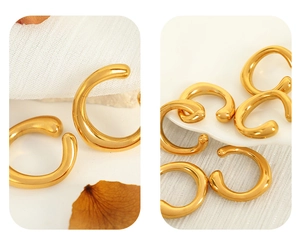 Polished gold C-shape ear cuffs showcased on white fabric with natural shadows and dried leaves