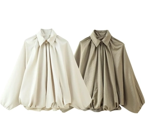 Detail of pleated satin long-sleeve blouse with lantern sleeves in white and olive green