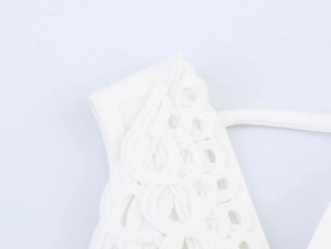Detailed macro view of white crochet lace stitching on a vacation style backless dress
