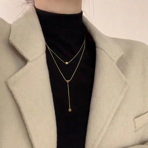Close-up of double-layered gold necklace with square pendants on a fashion model