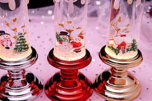 Close-up of three LED Christmas lanterns with snowman and Santa scenes in liquid