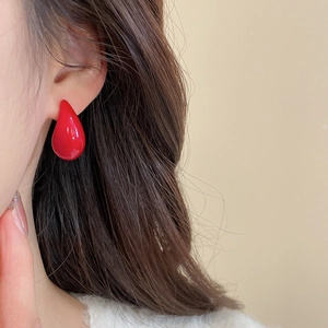 Close-up of a glossy red teardrop earring on model showing sleek acrylic material