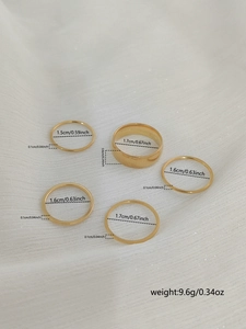 Detailed dimensions of five gold stackable stainless steel rings on white fabric