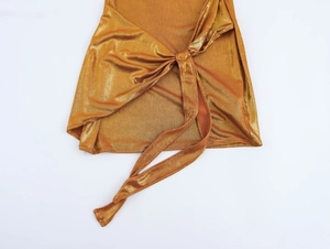 Détail du tissu pailleté doré avec design noué et texture métallique sur une robe