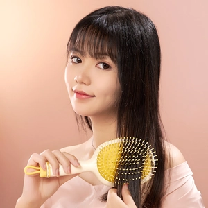 Cute cartoon bee print hair cushion brush used by a smiling model for long hair care