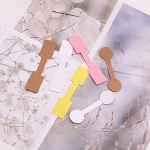 Flat lay of colorful dumbbell-shaped kraft paper jewelry labels in round and square styles