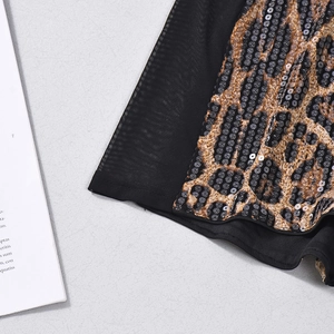 Detailed macro view of leopard print fabric with sequins and black mesh patchwork